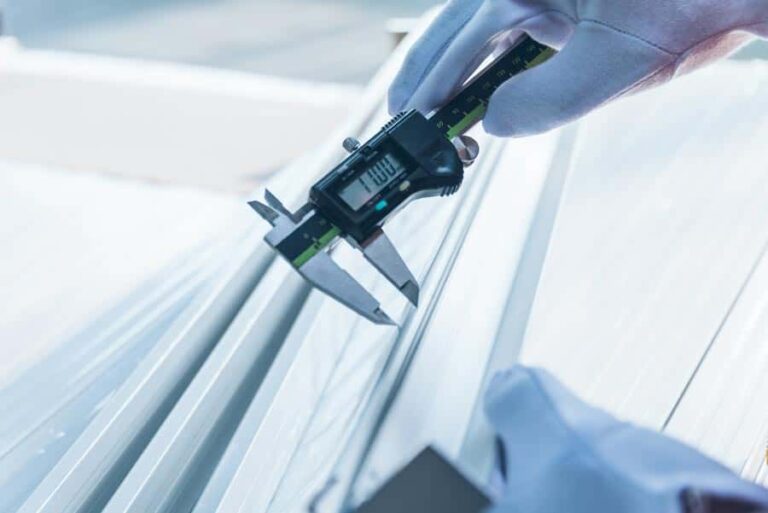 Precision Aluminum Products - Close up of an aluminum plant worker measuring precision of extruded aluminum with a caliper